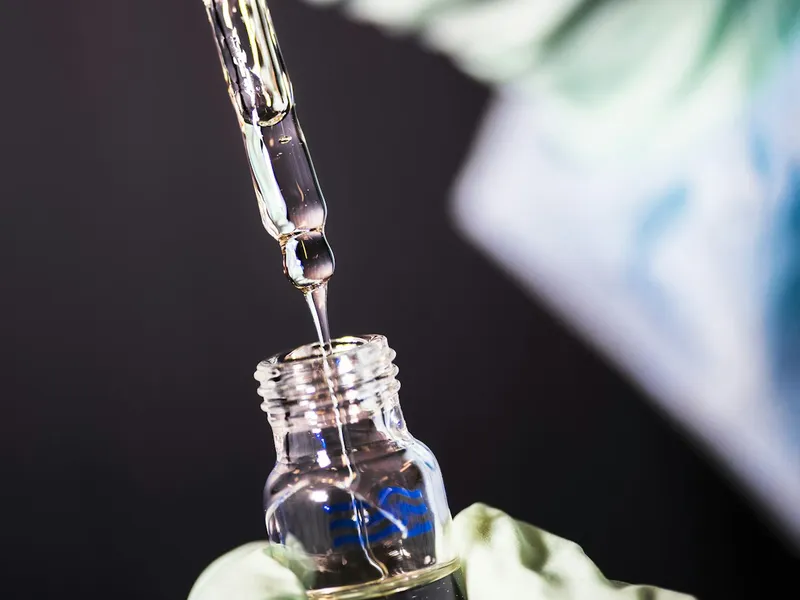 Eine Spritze zieht Impfstoff aus einer kleinen Ampulle auf