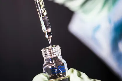 Eine Spritze zieht Impfstoff aus einer kleinen Ampulle auf